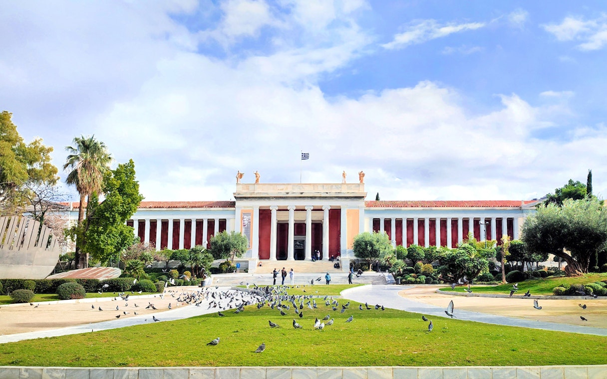 National Archaeological Museum facade with visitors and pigeons in Athens, Greece.
