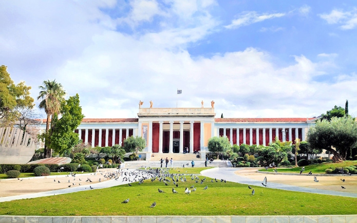 National Archaeological Museum facade with visitors and pigeons in Athens, Greece.