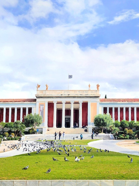National Archaeological Museum facade with visitors and pigeons in Athens, Greece.