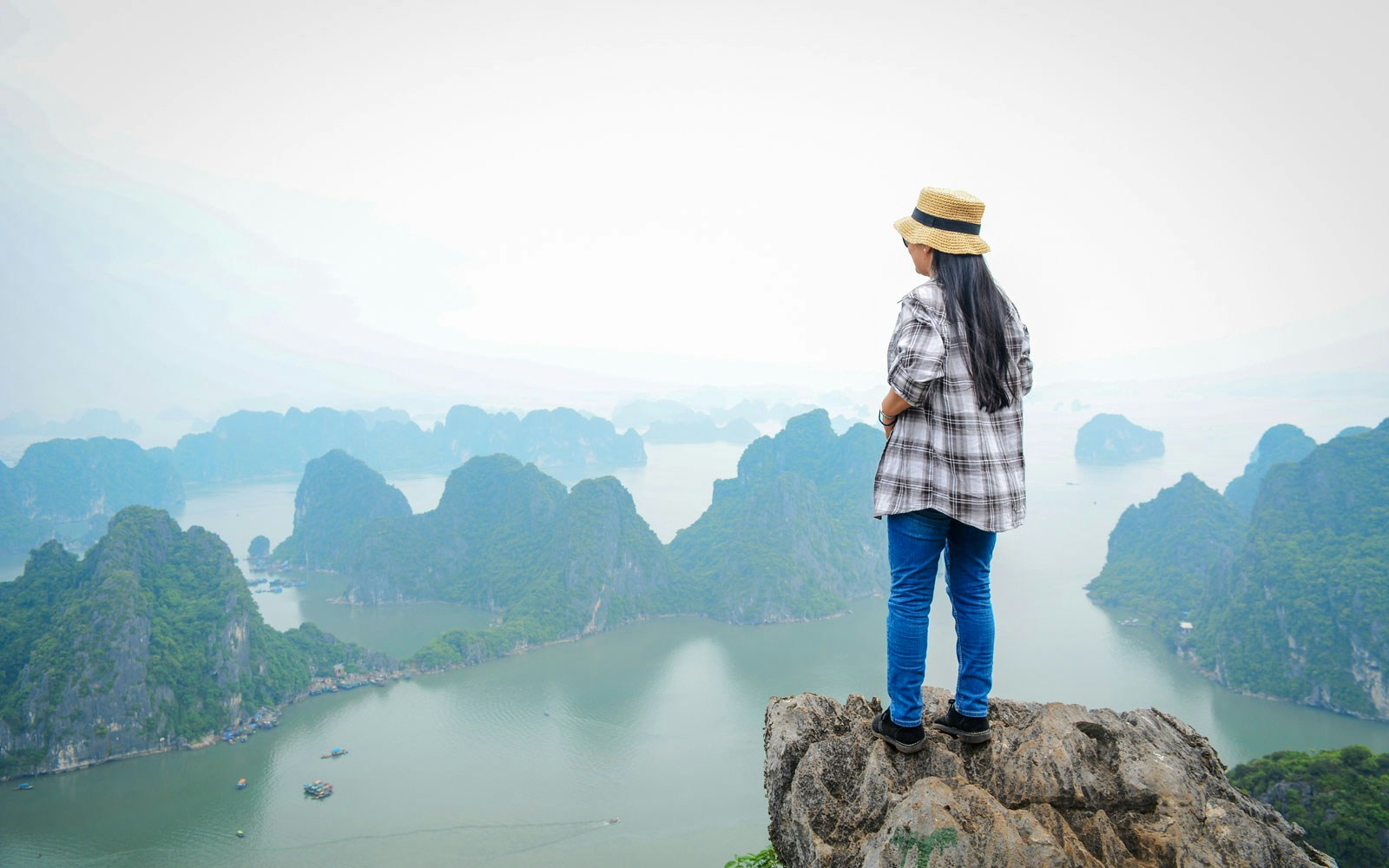 Person standing on a cliff overlooking Ha Long Bay, Vietnam.