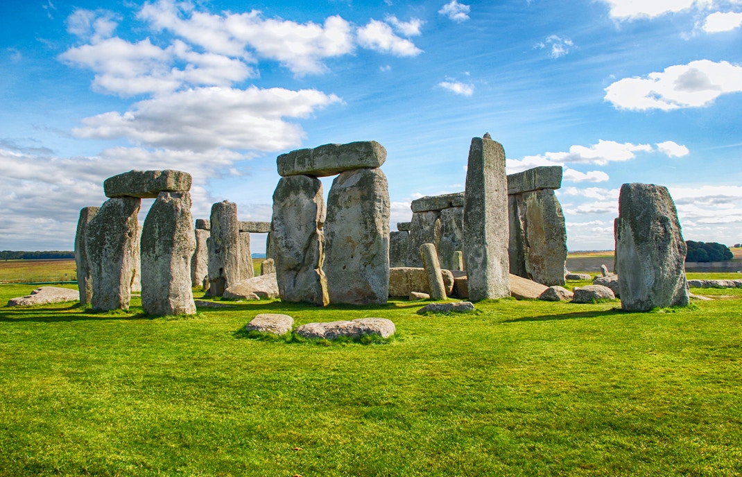 Stonehenge with tourists exploring the ancient stone monument on a day trip from London.