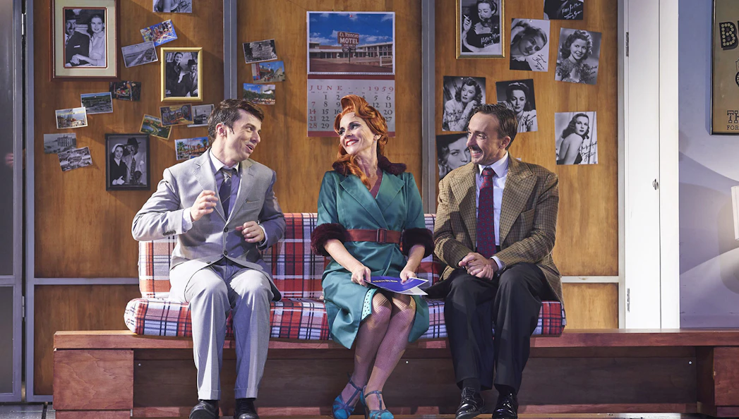 Three actors in vintage attire perform a scene from "The Producers" on stage.