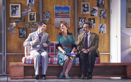 Three actors in vintage attire perform a scene from "The Producers" on stage.
