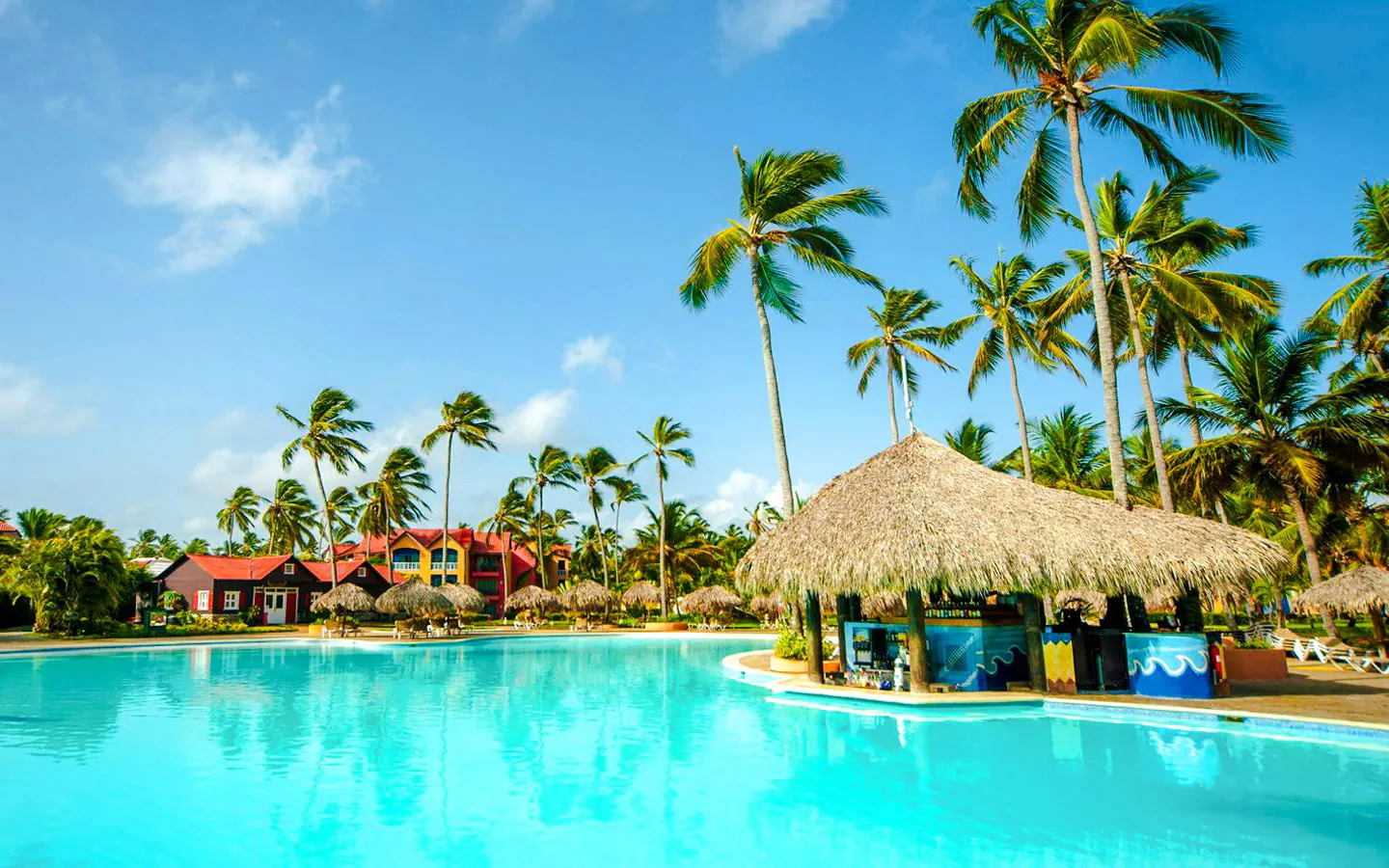 Large outdoor swimming pool with thatched-roof pool bar at Punta Cana Princess.