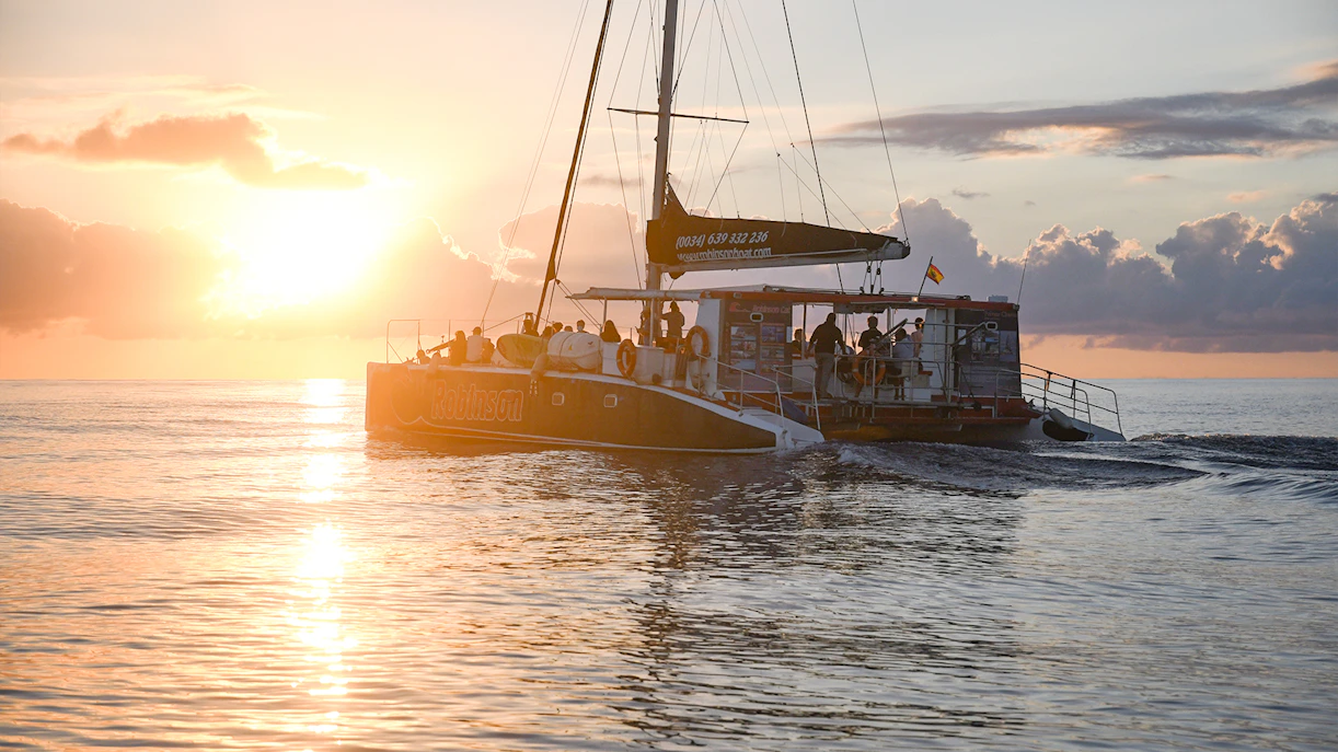 Catamaran sailing at sunrise in Mallorca for dolphin watching tour.
