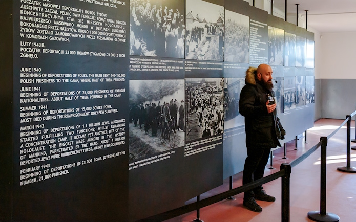 Guide explaining historical exhibits at Auschwitz Birkenau to visitors.