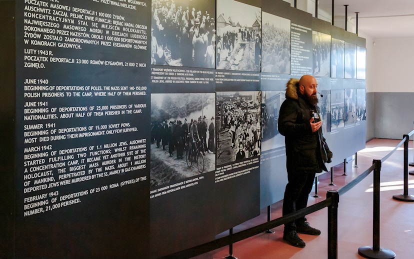 Guide explaining historical exhibits at Auschwitz Birkenau to visitors.