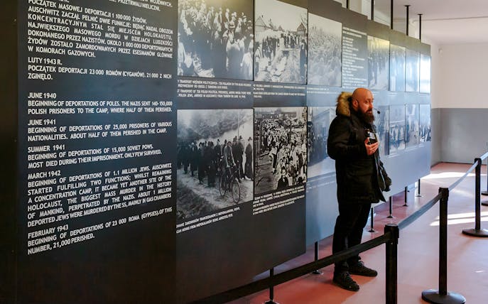 Guide explaining historical exhibits at Auschwitz Birkenau to visitors.