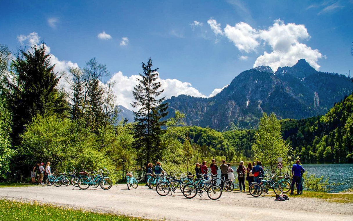 Group on a bike tour near Neuschwanstein Castle with mountain and lake views.