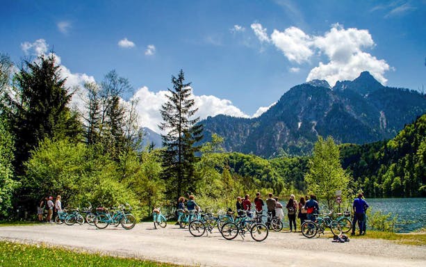 Group on a bike tour near Neuschwanstein Castle with mountain and lake views.