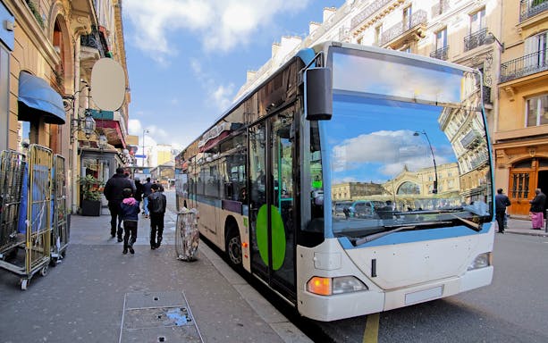 Paris public transport bus on city street with Eiffel Tower in background.