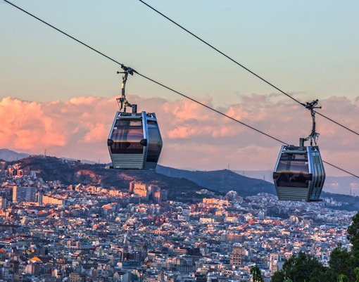 Cable car ascending Montjuic Hill with panoramic views of Barcelona cityscape.
