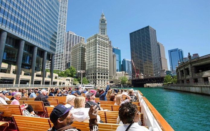 Visitors on Chicago River cruise viewing city architecture.