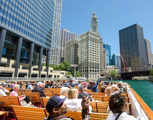 Visitors on Chicago River cruise viewing city architecture.