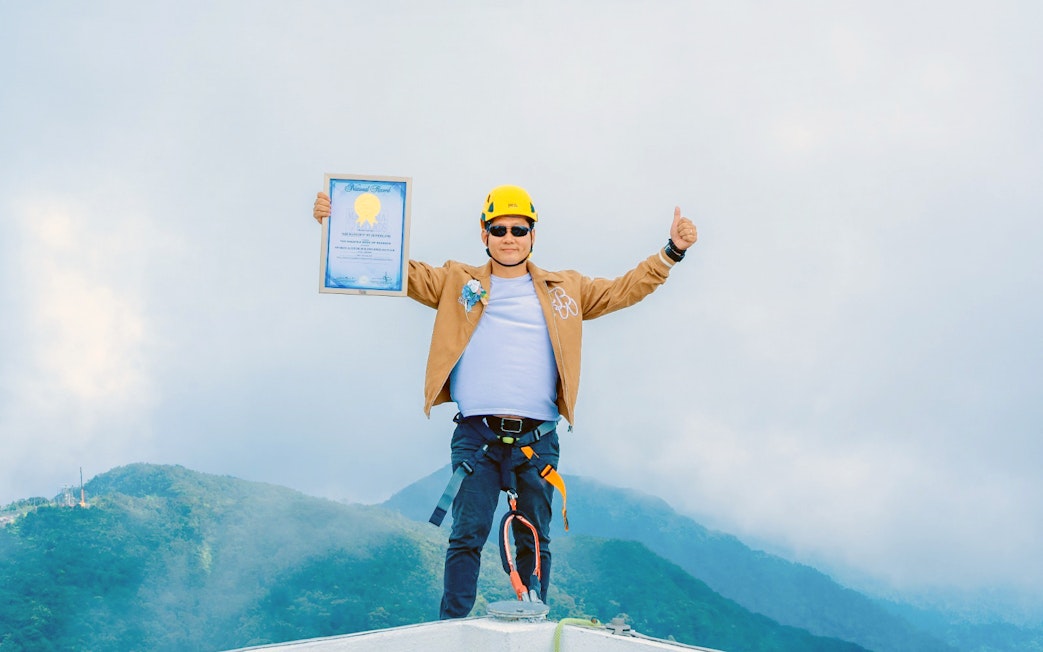 Tourist at Hoverland Genting holding a certificate with mountains in the background.