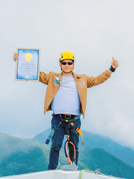 Tourist at Hoverland Genting holding a certificate with mountains in the background.