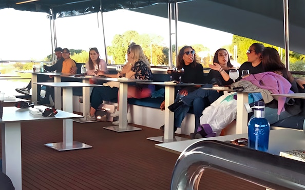 Tourists relaxing on a Seville Guadalquivir River sightseeing cruise.