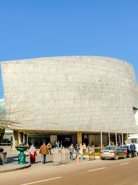 Bibliotheca Alexandrina exterior with hieroglyphic wall and ancient statue, Alexandria, Egypt.