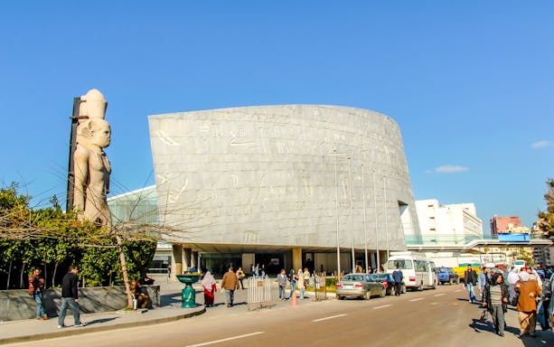 Bibliotheca Alexandrina exterior with hieroglyphic wall and ancient statue, Alexandria, Egypt.