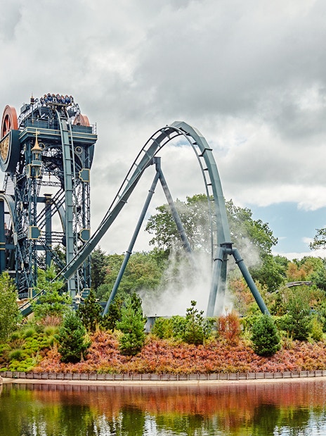 Dive coaster The Baron at Efteling amusement park, Netherlands, with riders and scenic surroundings.