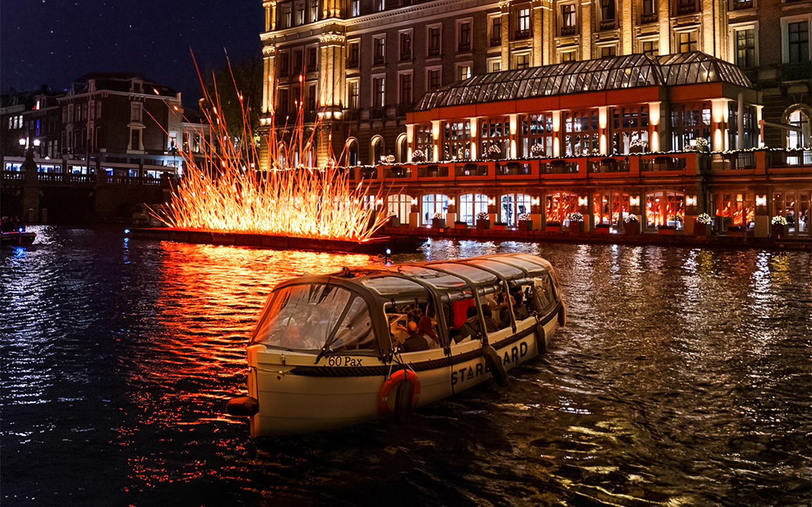 Small-group cruise passing illuminated art installation during Amsterdam Light Festival.