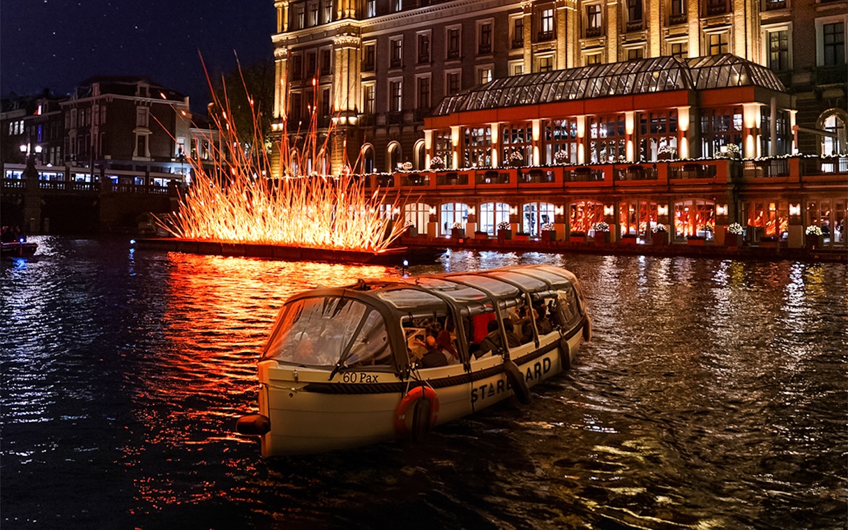 Small-group cruise passing illuminated art installation during Amsterdam Light Festival.