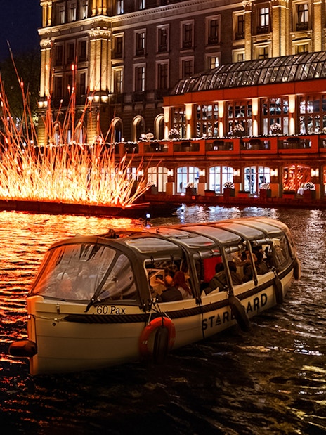 Small-group cruise passing illuminated art installation during Amsterdam Light Festival.