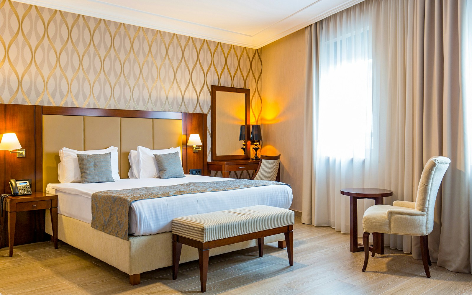 Mid-range hotel room with bed, desk, and window view in a city setting.