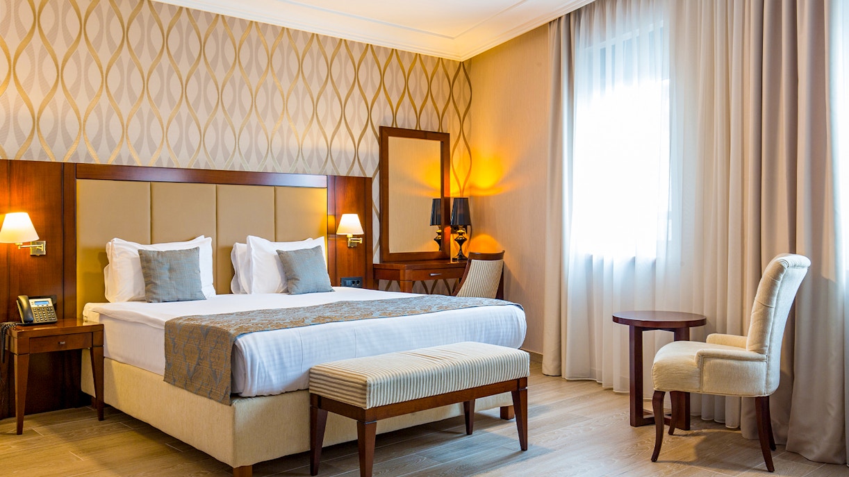 Mid-range hotel room with bed, desk, and window view in a city setting.