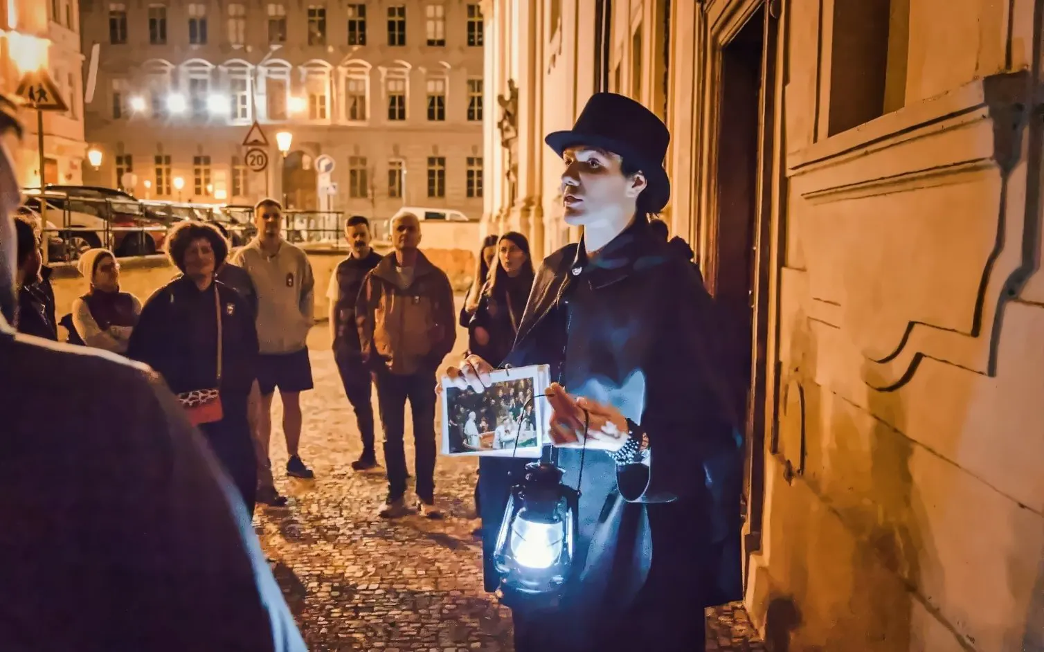 Guide leading Ghosts & Legends tour in Old Town Prague at night with lantern.