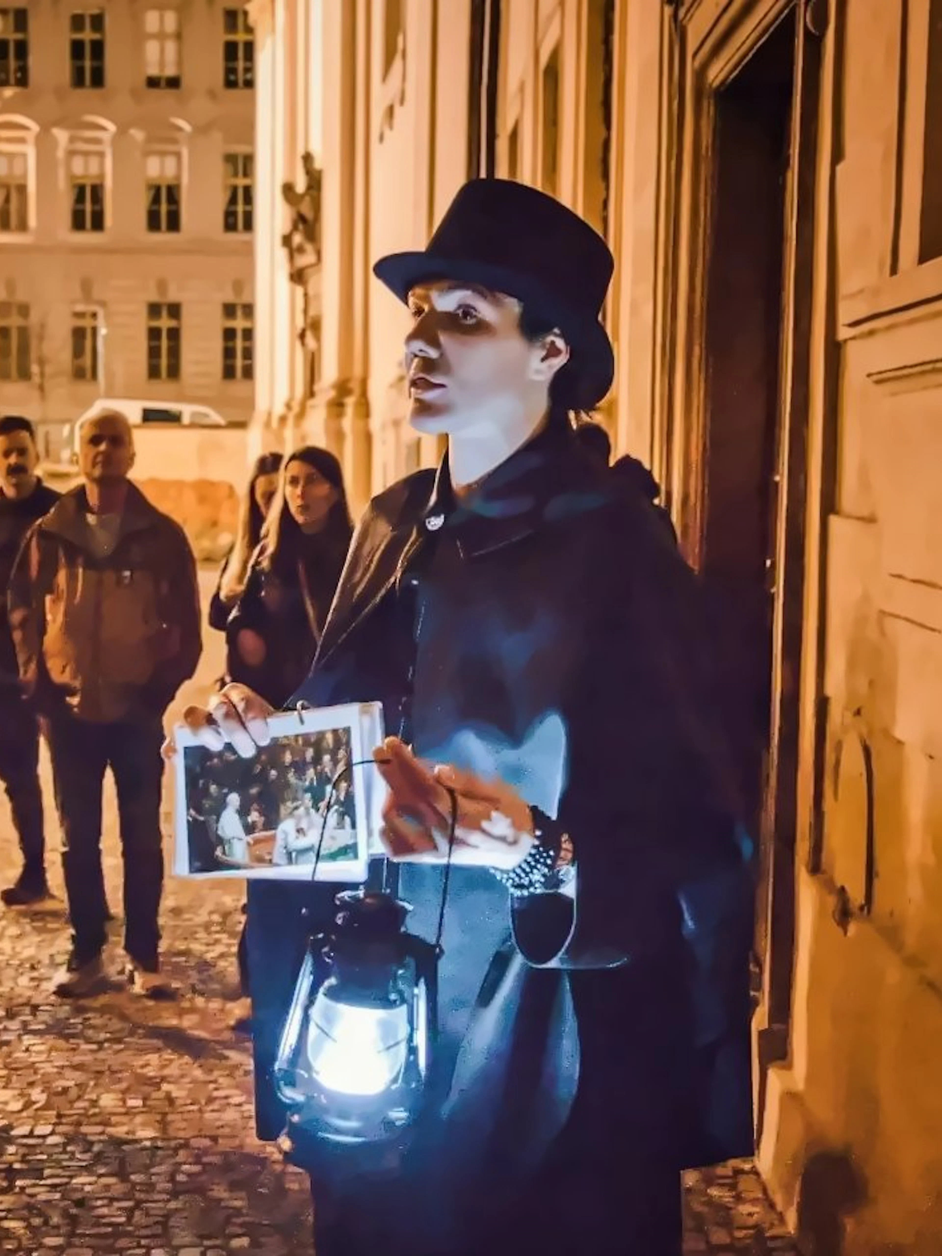 Guide leading Ghosts & Legends tour in Old Town Prague at night with lantern.