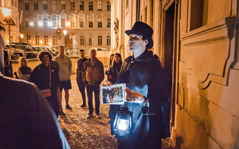 Guide leading Ghosts & Legends tour in Old Town Prague at night with lantern.