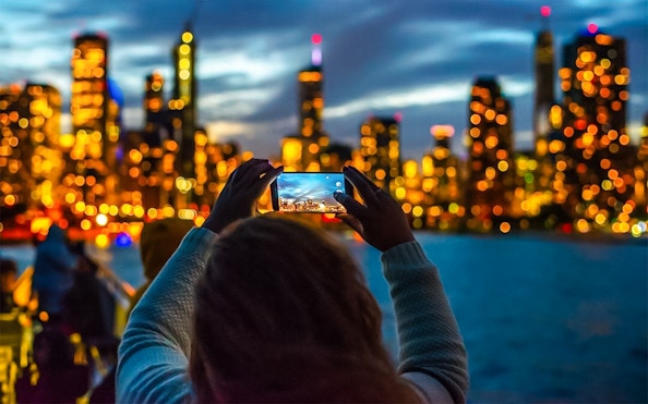 Person photographing Chicago skyline during Lake Michigan sunset cruise.