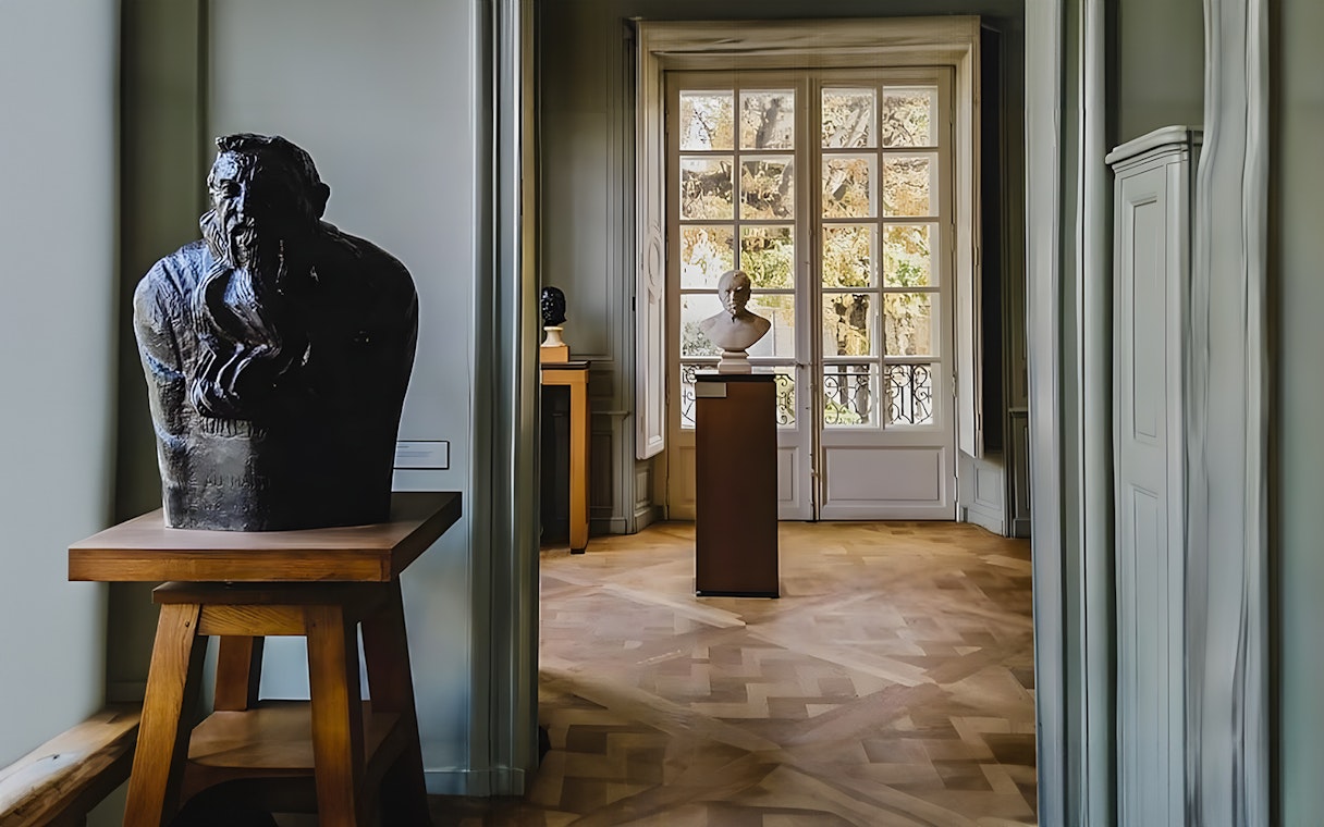 Rodin Museum interior with sculptures and large window view.