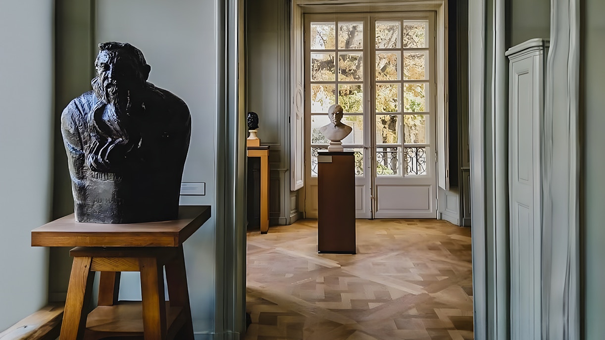 Rodin Museum interior with sculptures and large window view.