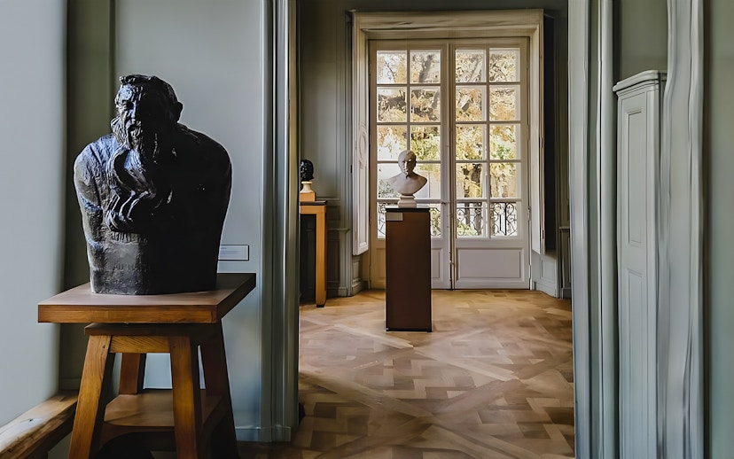 Rodin Museum interior with sculptures and large window view.