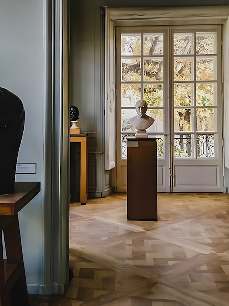 Rodin Museum interior with sculptures and large window view.