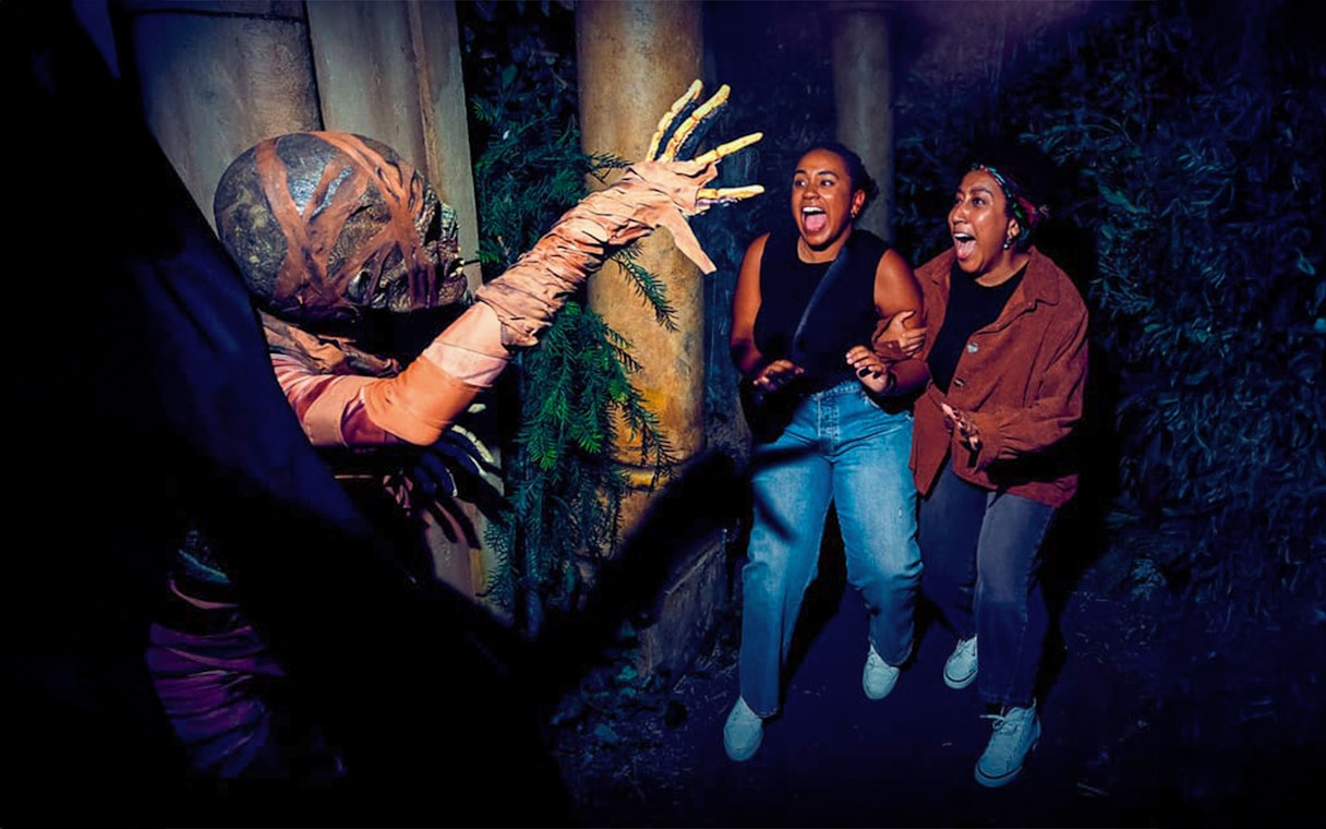 Guests react to a costumed performer at Universal Studios Hollywood Halloween Horror Nights.