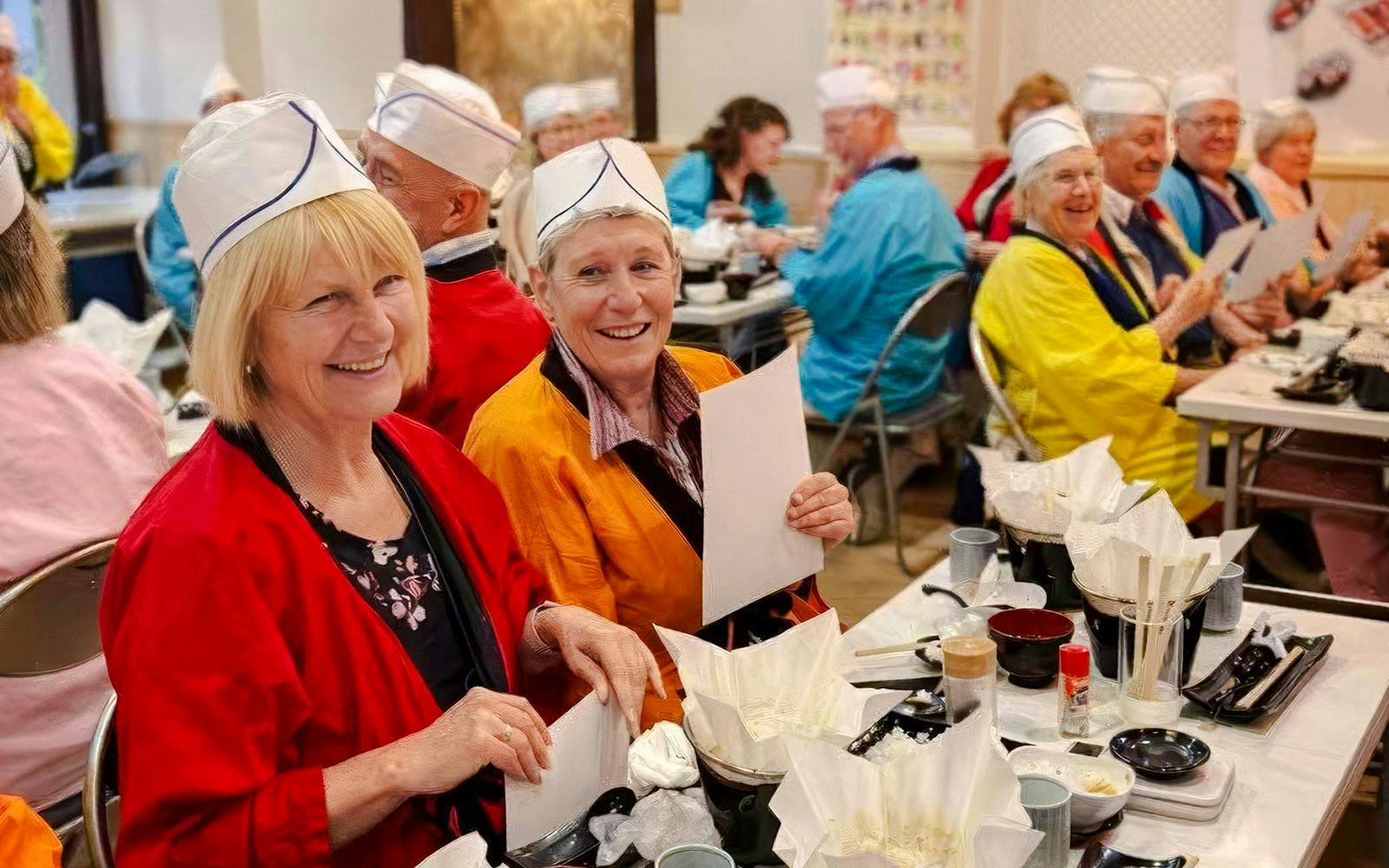 Tourists enjoying a sushi-making workshop in Osaka, wearing traditional attire.