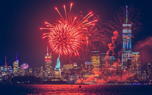 Fireworks display over the Statue of Liberty with New York City skyline.