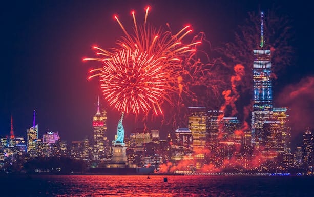 Fireworks display over the Statue of Liberty with New York City skyline.