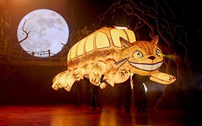 Stage production of My Neighbour Totoro with Catbus puppet and moon backdrop.