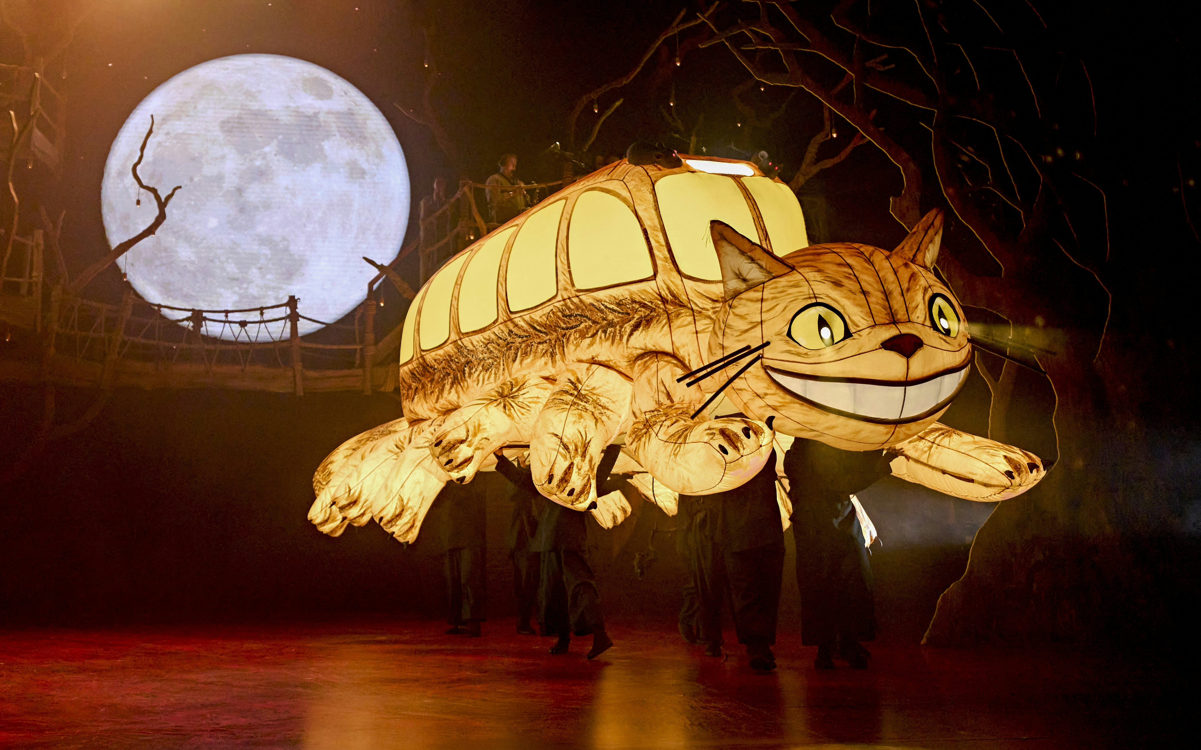 Stage production of My Neighbour Totoro with Catbus puppet and moon backdrop.