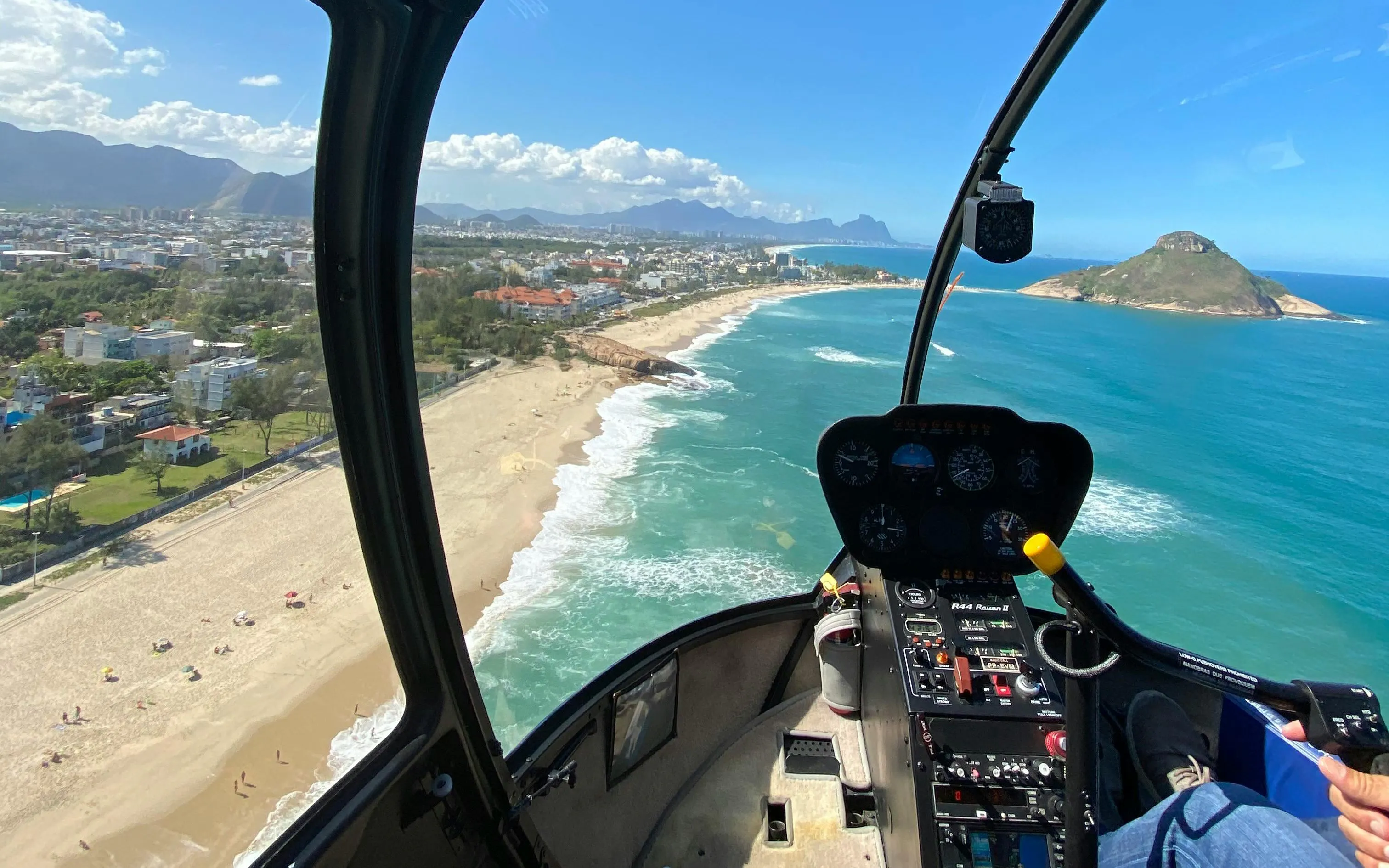Helicopter cockpit view of Rio de Janeiro beach coastline and ocean.