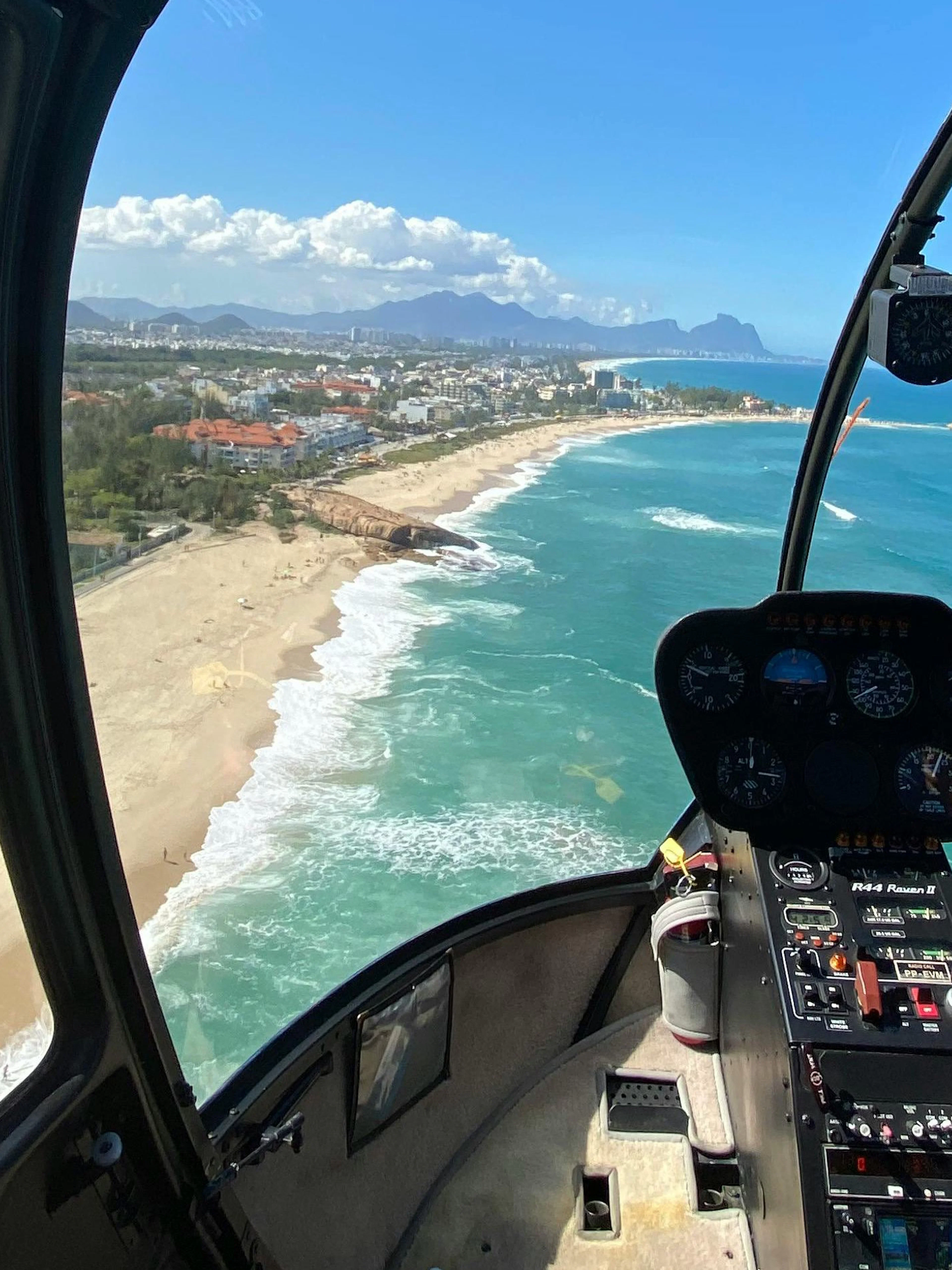 Helicopter cockpit view of Rio de Janeiro beach coastline and ocean.