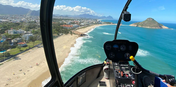 Helicopter cockpit view of Rio de Janeiro beach coastline and ocean.
