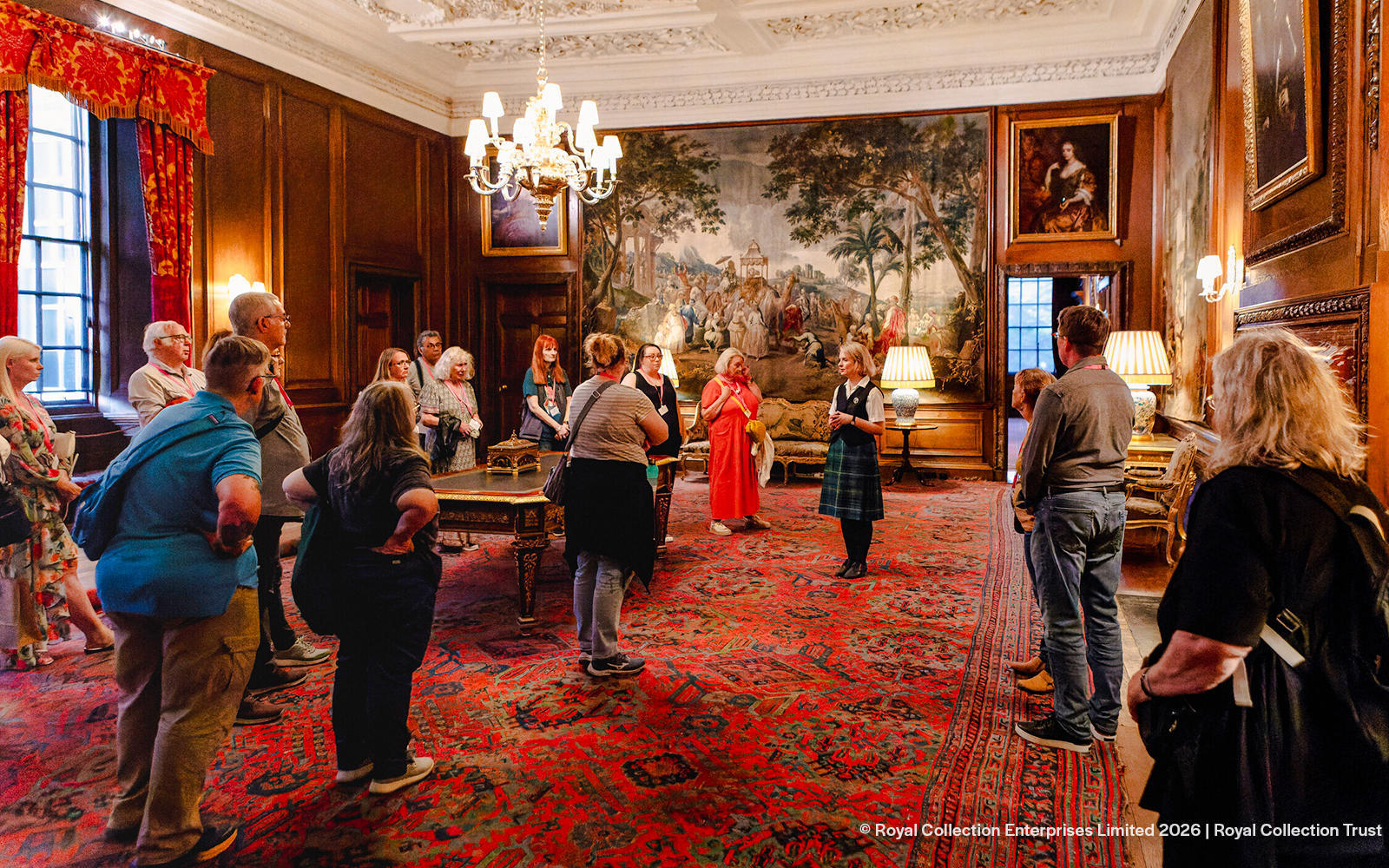Visitors on a guided tour inside the ornate room of Palace of Holyroodhouse, Edinburgh.