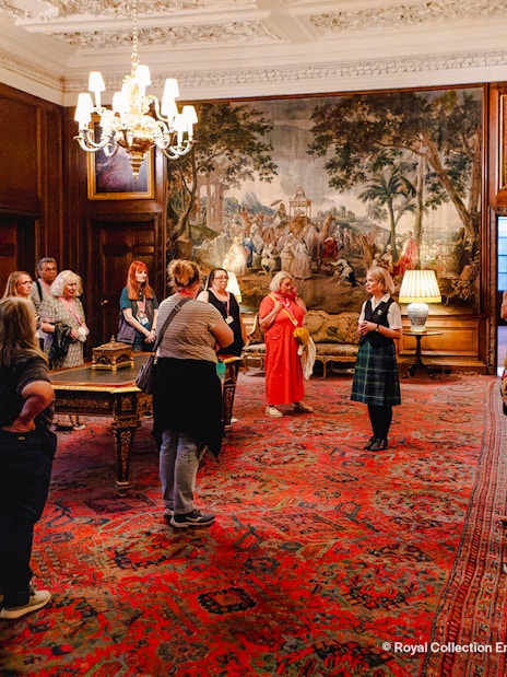 Visitors on a guided tour inside the ornate room of Palace of Holyroodhouse, Edinburgh.
