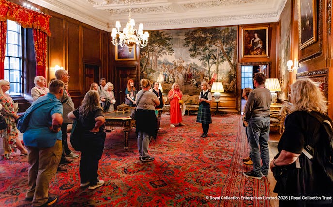 Visitors on a guided tour inside the ornate room of Palace of Holyroodhouse, Edinburgh.