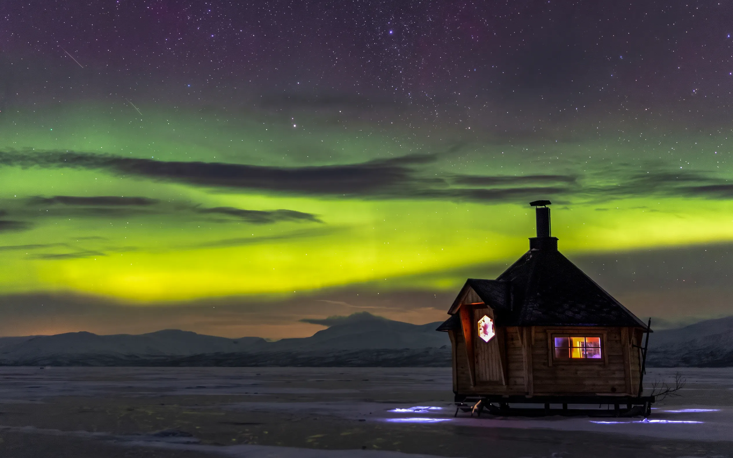 Northern lights over a cabin in Abisko during a photography tour.